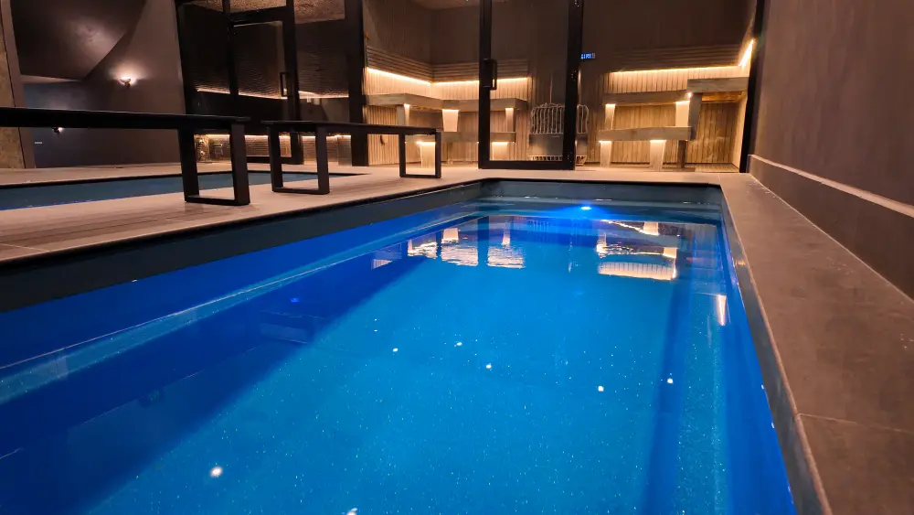 Illuminated commercial plunge pool beside saunas at a wellness venue